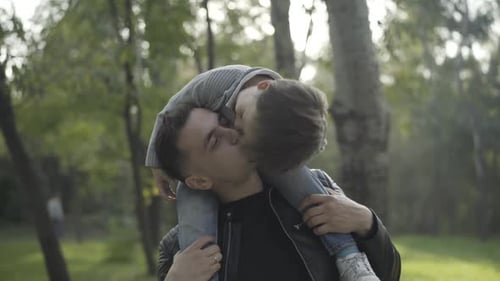 Father Carries Son on Shoulders in Sunny Park