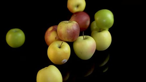 Vibrant Apples Tumble on a Black Reflective Surface
