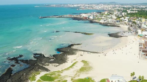 A wide sea with a view of the horizon and a beach with people enjoying a vacatio