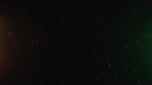 Natural Snowfall Winter Snow on Black Background with Colorful Orange and Green Light