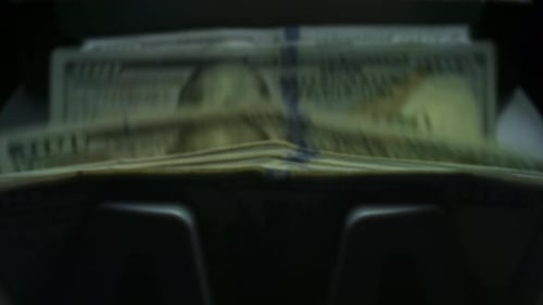 Currency Counter Counting Dollar Bills in Darkness