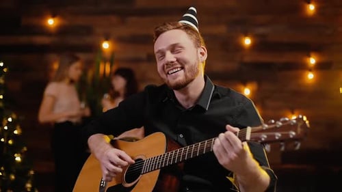 Man Plays Guitar at a Cozy Party