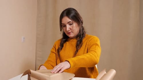 Woman Wrapping Birthday Present with Brown Paper