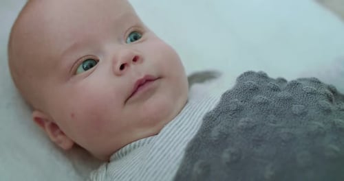 Close Portrait of Happy Newborn Baby Looking Around with Light Smile