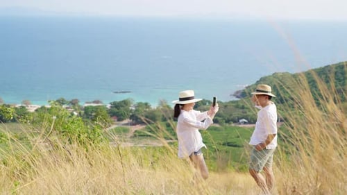 4K Asian couple using mobile phone photography together while travel on tropical island