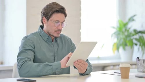 Mann mittleren Alters nutzt Tablet im Büro