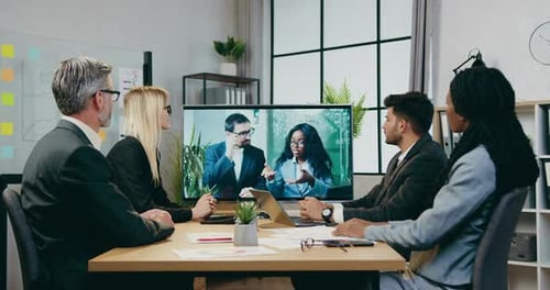 Empresarios votan durante una videoconferencia en línea con sus colegas en una moderna sala de juntas