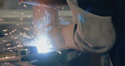 Welder welding metal parts in a workshop