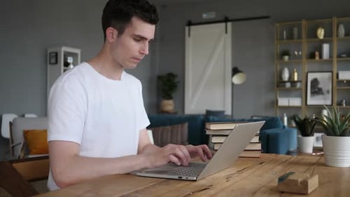 Young Adult Typing on Laptop, Coughing at Home