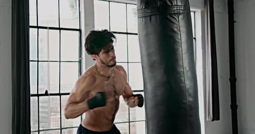 Muscular Man Boxing a Punching Bag in Gym
