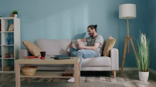 Man Relaxing on Couch Using a Tablet