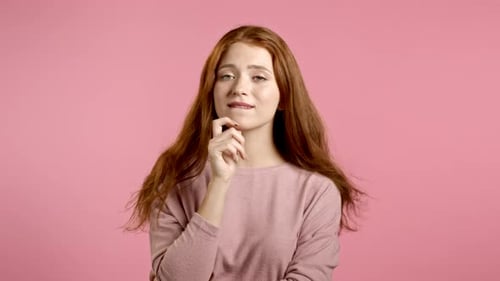 Woman with Auburn Hair Thinking on Pink Background