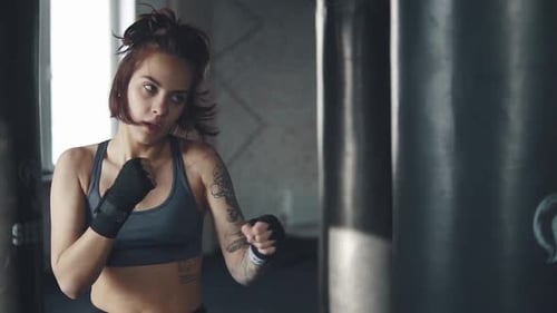 Kickboxing Woman Training Punching Bag in Fitness Studio