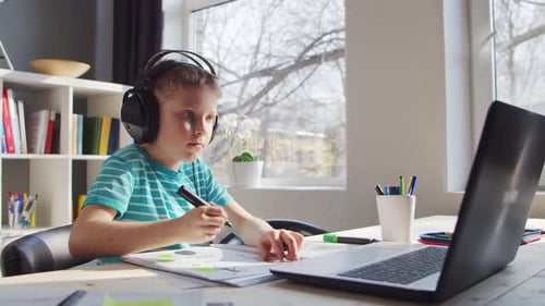 Boy Drawing with Headphones and Laptop Indoors
