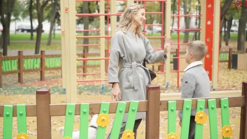 Wide Shot Portrait of Happy Caucasian Beautiful Mother Enjoying Autumn Weekend in Park with Son and