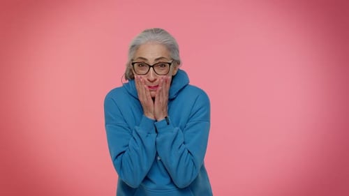 Senior Woman Reacting with Surprise on Pink Background