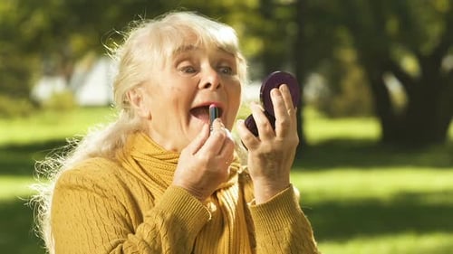 Senior Women Applying Lipstick in Autumn Park
