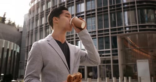 Man Walks and Eats Lunch in City Center