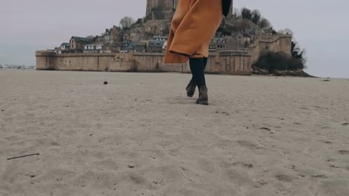 Woman in Coat Walks to Coastal European Castle