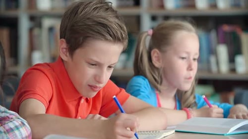 Children Studying Together Diligently Writing in Notebooks