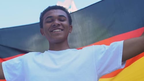 Afroamerikanischer Teenager-Junge schwenkt deutsche Flagge im Freien