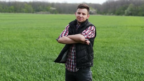 Porträt eines erfolgreichen Landwirts, der im grünen Weizenfeld in die Kamera blickt