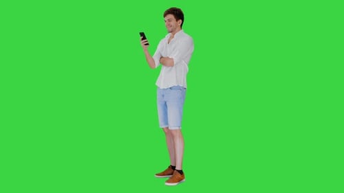 Handsome Young Man Using His Smartphone and Laughing on a Green Screen, Chroma Key
