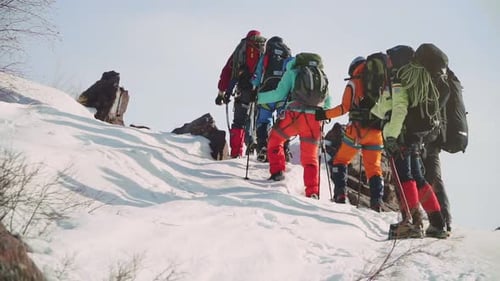 Langsam und stetig steigt ein solides Team von Kletterern am Hang entlang und tritt in die Schneewinde ein.