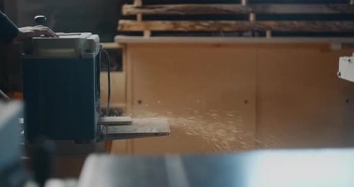Carpenter Uses Electric Planing Machine at His Woodworking Workshop Timber Shavings and Sawdust Fall