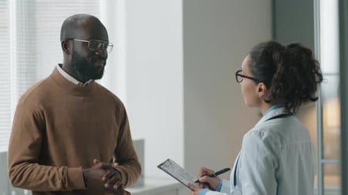 Female Doctor Speaking with Black Patient in Clinic