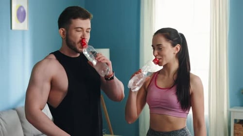 Athletic Couple Rehydrating After a Workout at Home