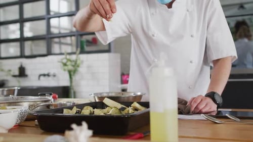 Chef Preparing Eggplant Wearing Mask in Modern Kitchen