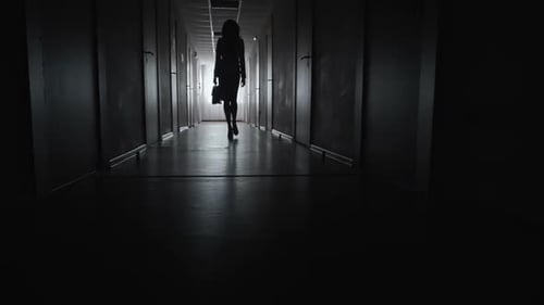 Silhouetted Woman Walking Darkly Lit Hallway