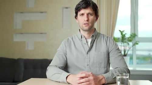 Man Seated Indoors Talking and Gesturing