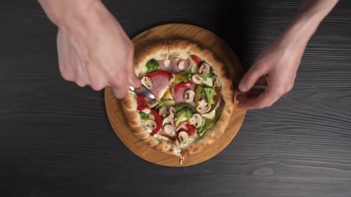 Male Hands Cut Pizza with Pizza Knife on Wooden Background