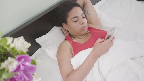 Woman Lying in Bed Using a Cellphone