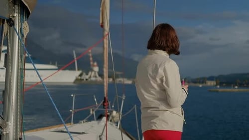 Back woman stands looking into the distance and stands on Deck of the sailing boat moving in a sea