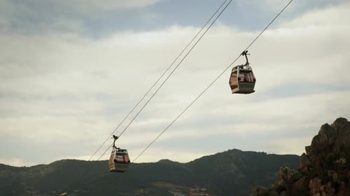 Cable road cabin going down against grey cloudy sky. Mountain cable car
