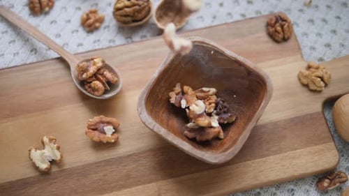 Walnut Pieces Falling into a Wooden Bowl