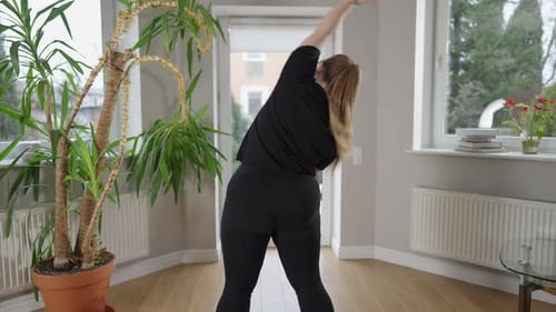 Back View of Motivated Overweight Caucasian Woman Bending Warming Up Training Indoors