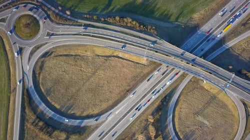 Aerial view of freeway intersection with moving traffic cars.