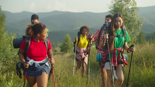 Portrait of Diverse Travelers with Backpacks and Hiking Poles Ascending Mountain Hill