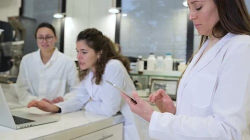 Scientists Work Together in Lab Using Tablet and Laptop