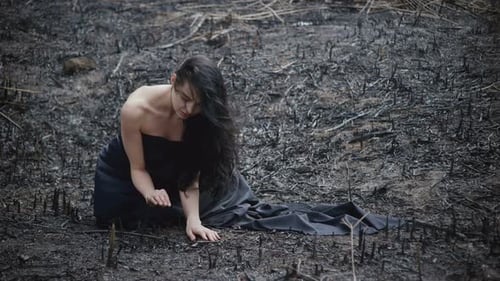 Woman Kneeling in a Charred, Post-Apocalyptic Field
