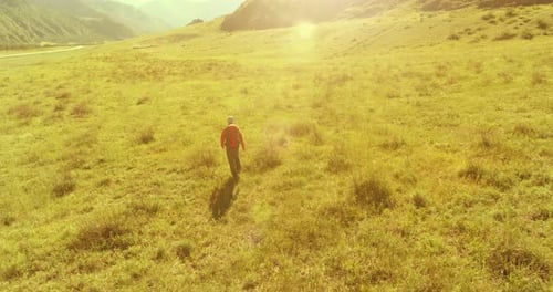 Flight Over Backpack Hiking Tourist Walking Across Green Mountain Field