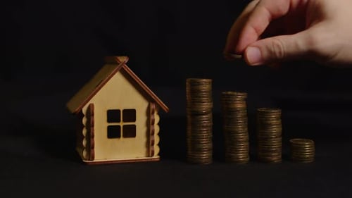 Small Wooden House with Columns of Coins on Black Background