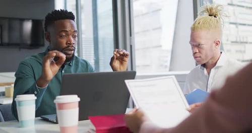 Diverse business people discussing with documents in creative office