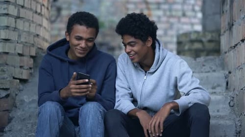 Two Friends Laughing Together at Mobile Phone