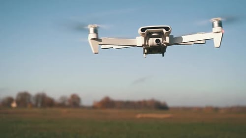 White Drone Flying on Nature Background. Drone Hanging in Air Flying Helicopter Dron Remote Control