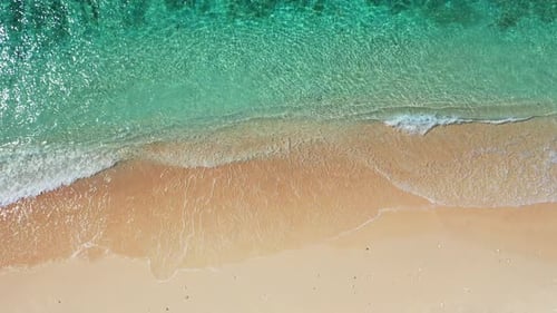 Wide aerial travel shot of a sandy white paradise beach and turquoise sea background in colorful 4K